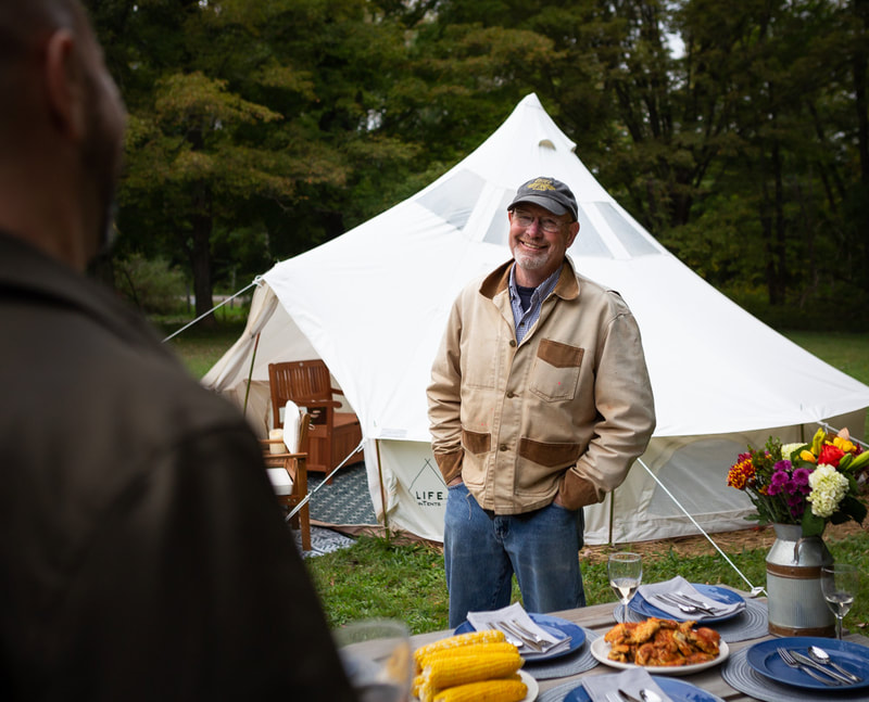 Man smiling in front of a tent by a picnic table at Panama Rocks
