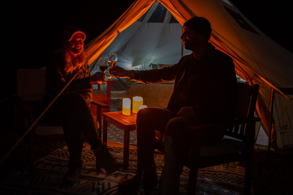 Couple clicking drinks sitting in front of a tent at Panama Rocks